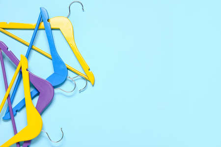 Stylish clothes hangers on color background