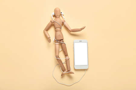Mannequin with modern earphones and mobile phone on color backgroundの写真素材