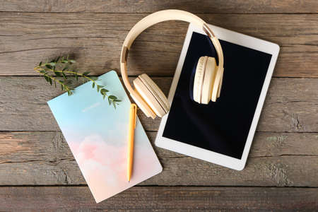 Modern headphones, tablet computer and notebook on wooden backgroundの写真素材