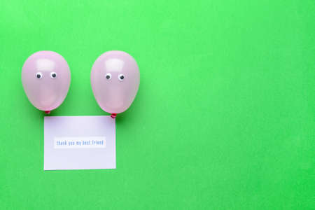 Funny air balloons and greeting card for Friendship Day on color background