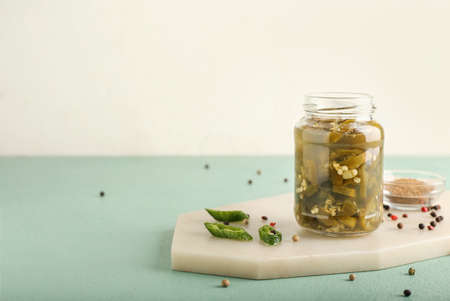 Glass jar with canned jalapeno on color backgroundの写真素材