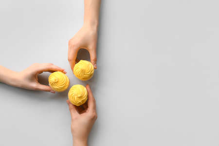 Female hands with cupcakes on gray backgroundの写真素材
