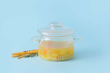 Stylish cooking pot with hot soup and ingredients on color backgroundの写真素材