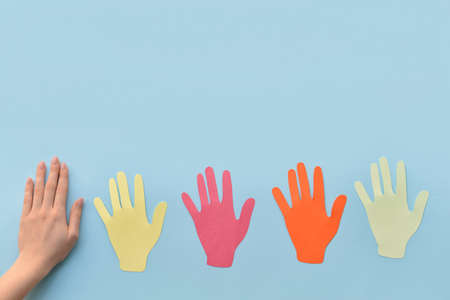 Female hand with paper human palms on color backgroundの写真素材