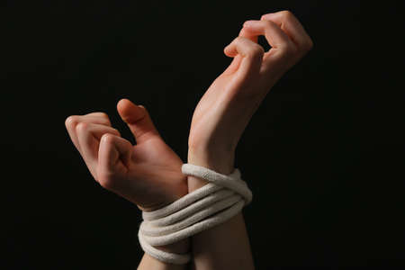 Female hostage with tied hands on dark background, closeupの写真素材