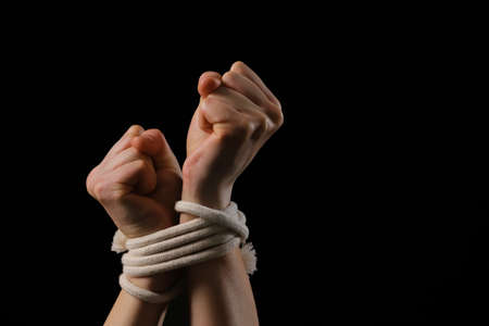 Female hostage with tied hands on dark background, closeupの写真素材