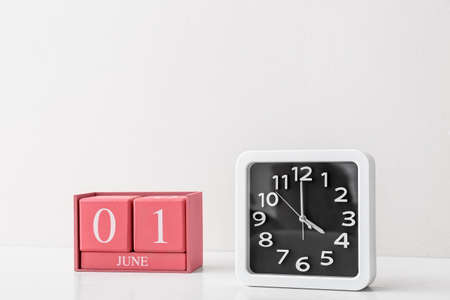 Stylish clock and cube calendar on table near light wallの写真素材