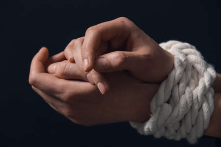 Female hostage with tied hands on dark background, closeupの写真素材