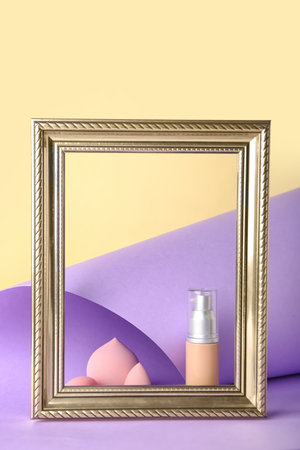 Frame with makeup sponges and foundation on color backgroundの写真素材