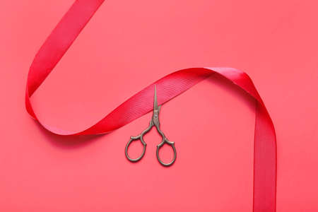 Red ribbon and scissors on color backgroundの写真素材
