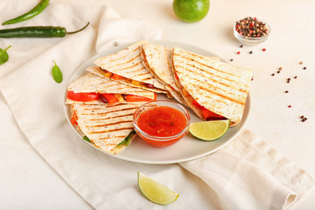 Plate with tasty vegetarian quesadillas and sauce on light backgroundの写真素材