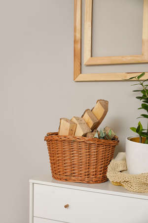 Basket with firewood on shelf near light wall