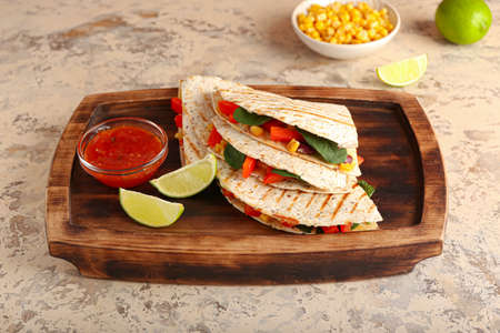 Tray with tasty vegetarian quesadillas, lime and sauce on light background