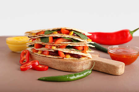 Board with tasty vegetarian quesadillas, sauces and vegetables on tableの写真素材