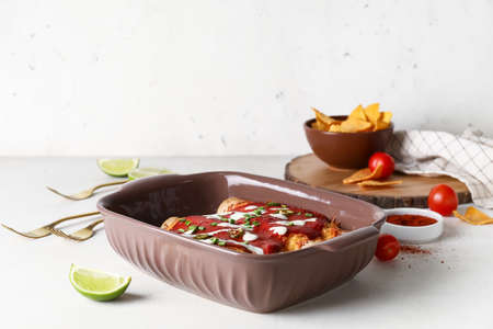 Baking dish with tasty cooked enchilada on table