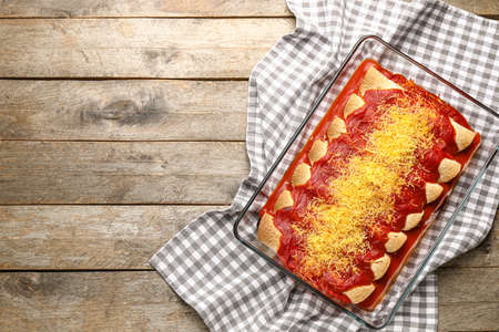 Baking dish with tasty cooked enchilada on tableの写真素材