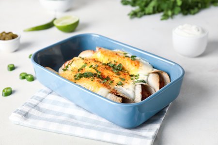 Baking dish with tasty cooked enchilada on tableの写真素材