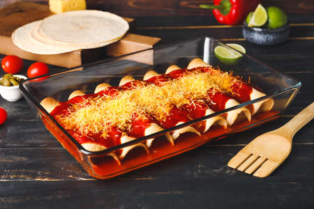 Baking dish with tasty cooked enchilada on tableの写真素材