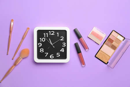 Composition with stylish clock and decorative cosmetics on color backgroundの写真素材