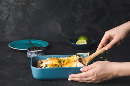 Woman with hot enchilada in baking dishの写真素材
