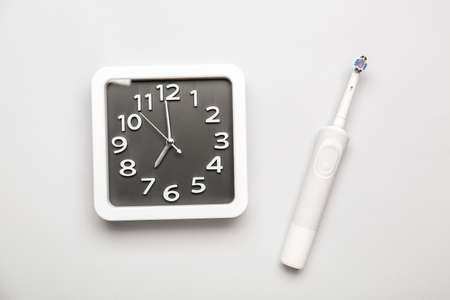 Stylish clock and tooth brush on light backgroundの写真素材