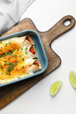 Baking dish with tasty cooked enchilada on table