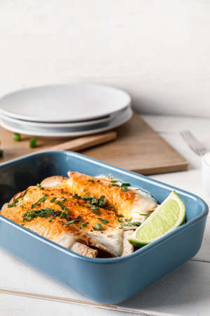 Baking dish with tasty cooked enchilada on table