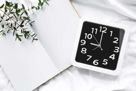 Stylish clock and notebook on bedの写真素材