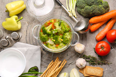 Stylish cooking pot with tasty soup and ingredients on grunge backgroundの写真素材