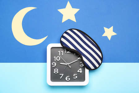 Composition with stylish clock and sleeping mask on color background