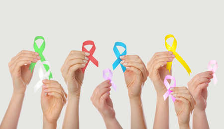 Many hands holding different ribbons on gray background. World Cancer Day