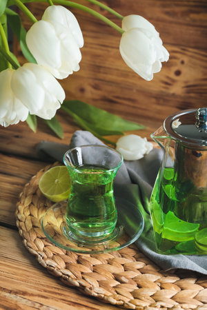 Composition with hot green tea and tulips on wooden backgroundの写真素材