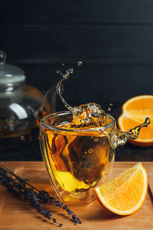 Glass of hot citrus tea with splash on dark backgroundの写真素材
