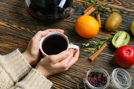 Woman with cup of hot fruit tea at wooden tableの写真素材