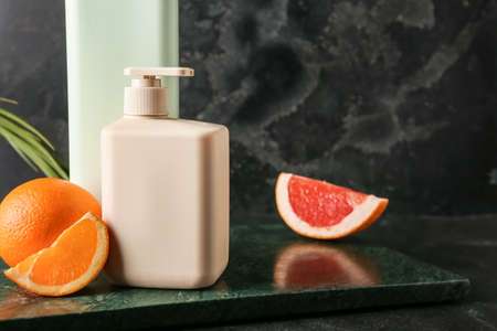 Bottles of shower gel and fruits on dark background