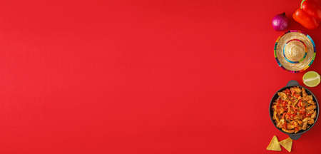 Frying pan with tasty Mexican Fajita and sombrero hat on red background with space for text