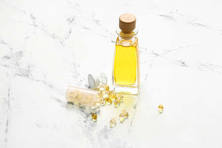 Bottles of fish oil and capsules on light background