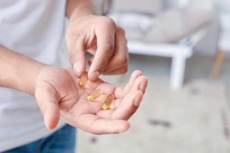 African-American teenage boy with fish oil pills at home, closeupの写真素材