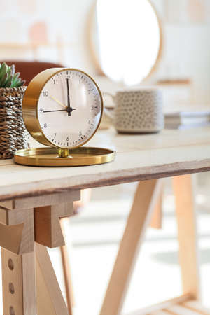 Stylish alarm clock on table in room