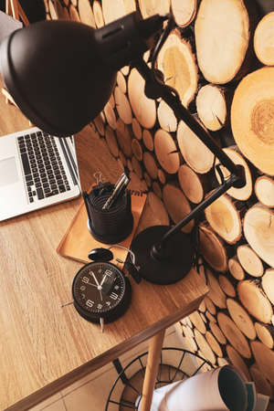 Alarm clock and lamp on table near wooden wallの写真素材