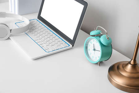 Stylish alarm clock and laptop on tableの写真素材