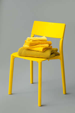 Chair with stack of stylish clothes on gray backgroundの写真素材