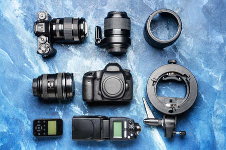 Modern photographer's equipment on color background