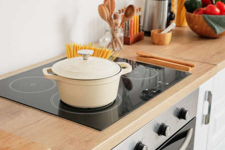 Cooking pot with pasta on stove in kitchenの写真素材