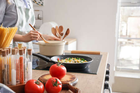 Woman cooking on kitchen stove, closeupの写真素材