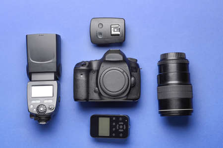 Modern photographer's equipment on color background