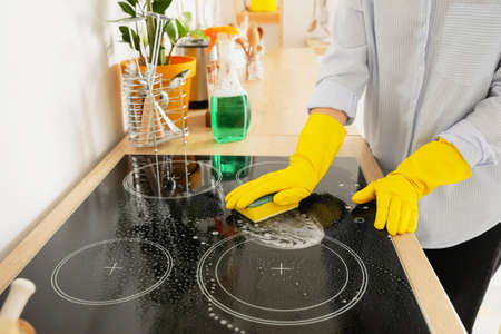 Woman cleaning stove in kitchen, closeupの写真素材
