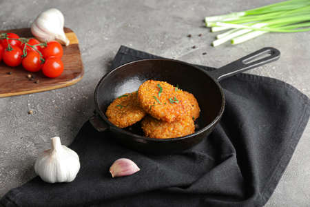 Frying pan with tasty lentil cutlets on grunge background