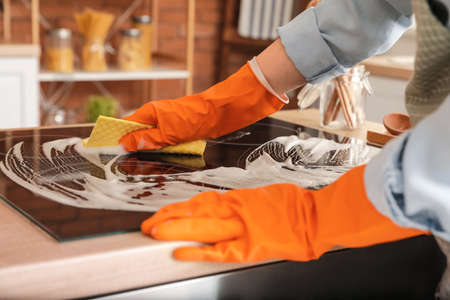 Woman cleaning stove in kitchen, closeupの写真素材