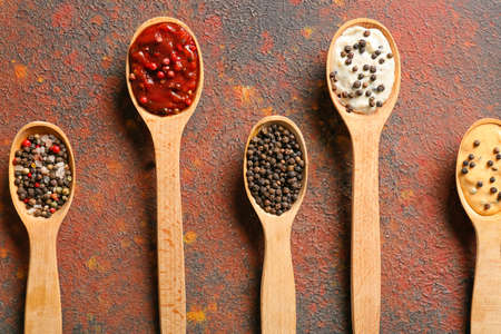 Spoons with different sauces and peppercorns on grunge backgroundの写真素材